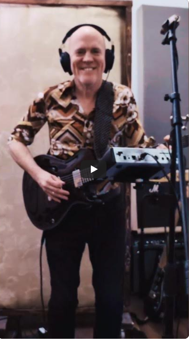 eric playing guitar and smiling